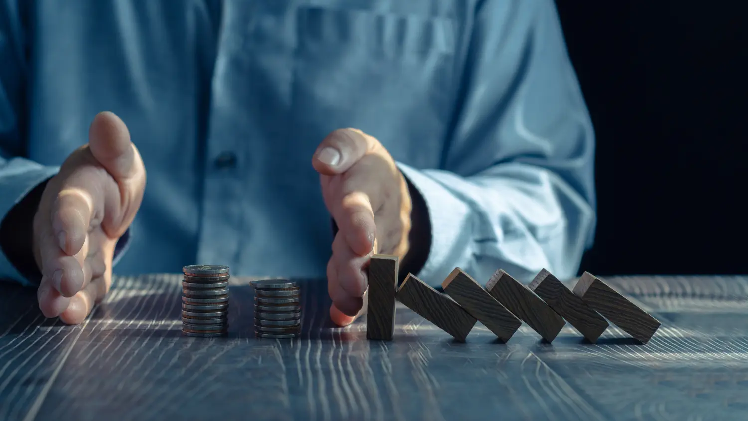 Konzept des wirtschaftlichen Zusammenbruchs, Hände stoppen Domino-Kriseneffekt